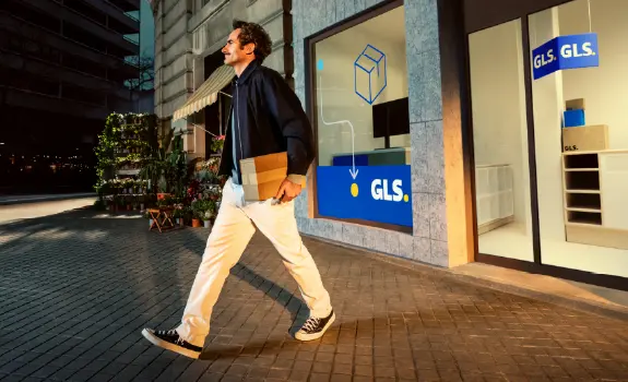 Mies kävelee GLS-noutopisteestä paketti kädessä