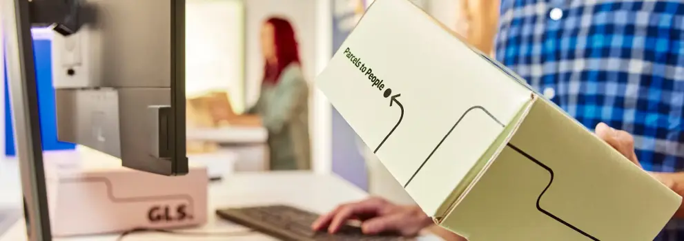 Gros plan sur un client remettant un colis GLS à un comptoir d’expédition, illustrant une solution d’envoi dédiée aux professionnels.